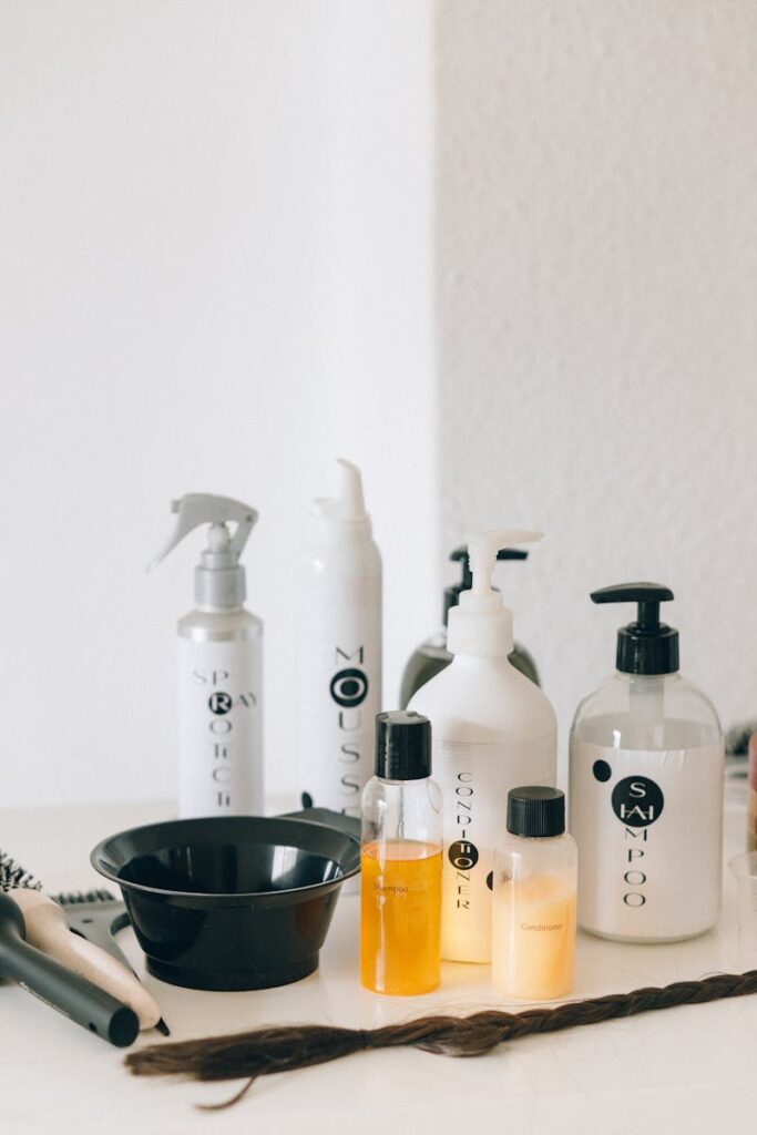 A collection of haircare bottles on a white counter with styling tools.