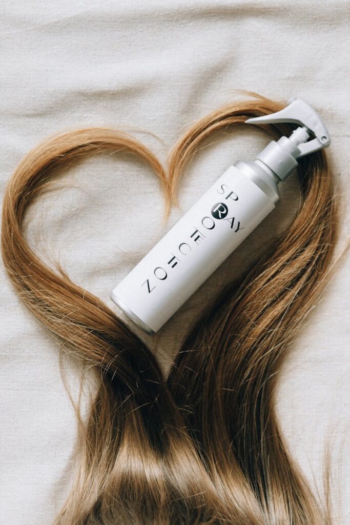 Hair product bottle surrounded by hair in heart shape on fabric, showcasing elegant hair care.