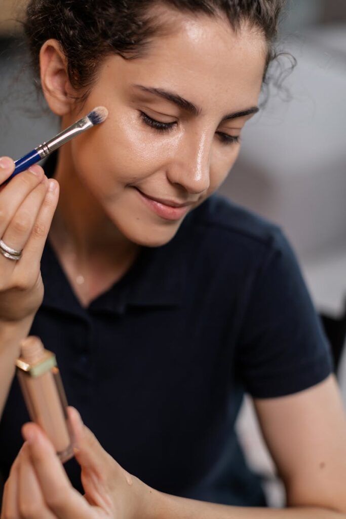 Close-up of a woman elegantly applying cosmetics using a brush indoors.