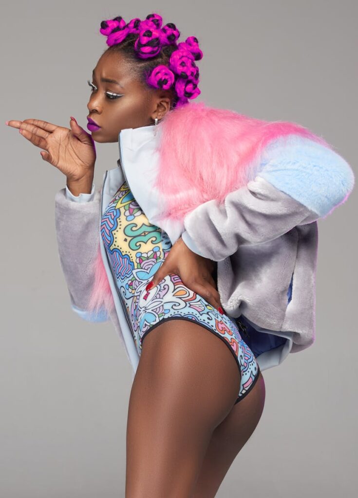 A vibrant fashion portrait of a woman posing with colorful hair and attire.