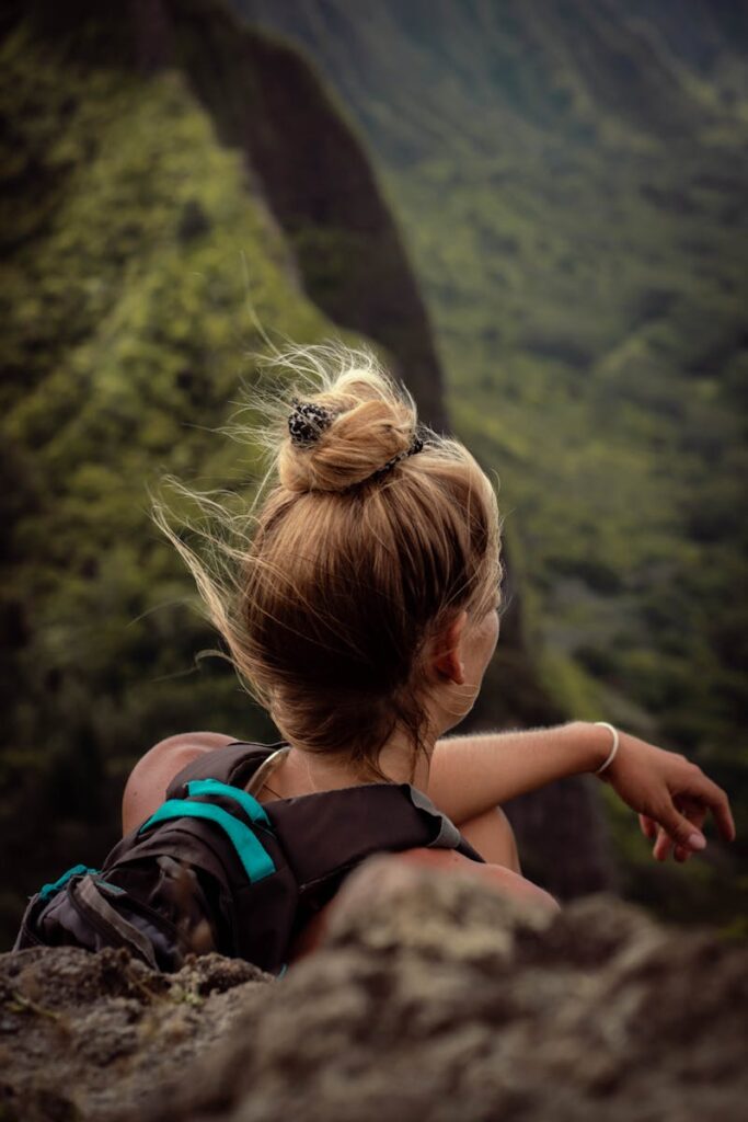 A woman with a backpack enjoys a breathtaking view of a lush mountain landscape, perfect for adventure seekers.