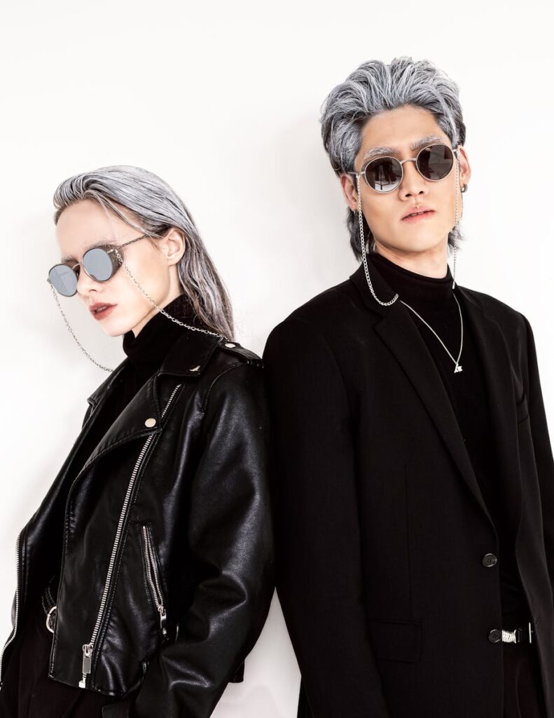 Two models in stylish black jackets and sunglasses posing against a white background.