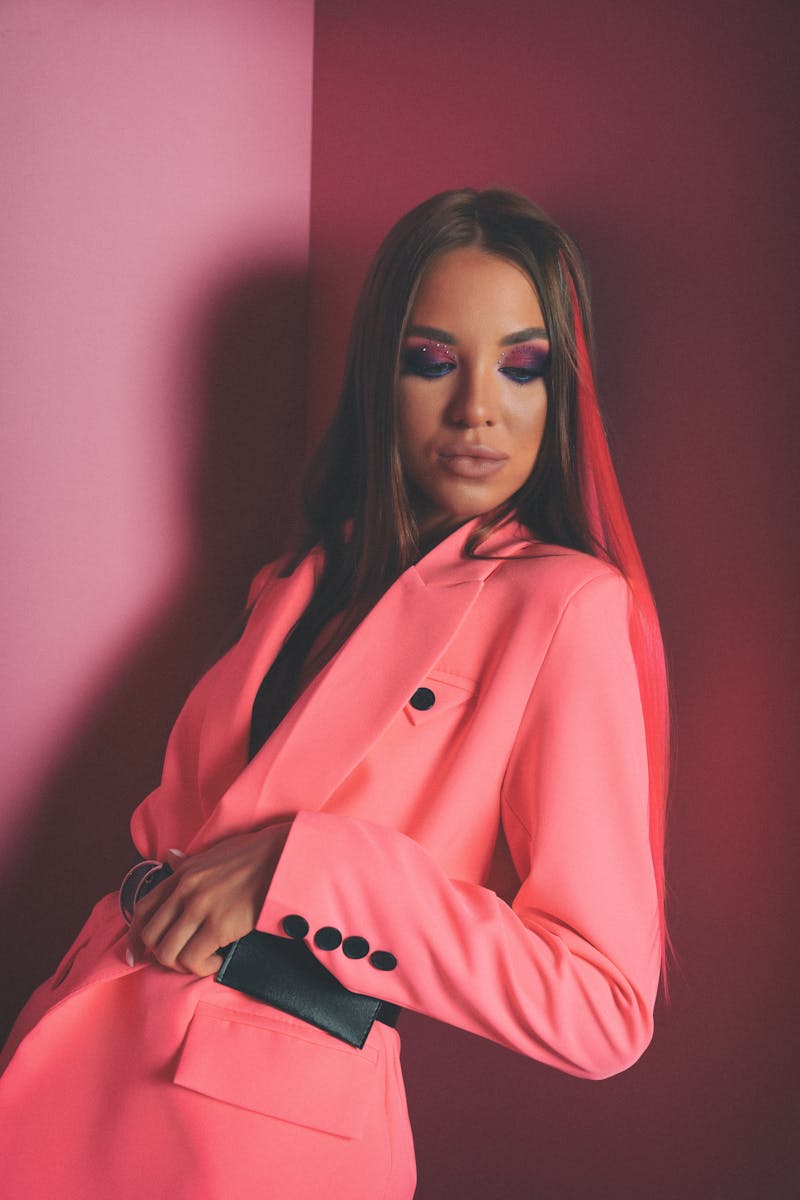 Stylish portrait of a woman in a pink suit against a matching background.