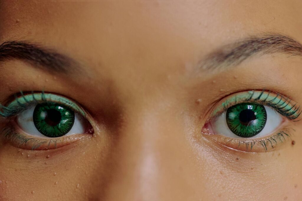 Close-up of a woman's vibrant green eyes with artistic makeup. A captivating and vivid representation of beauty.
