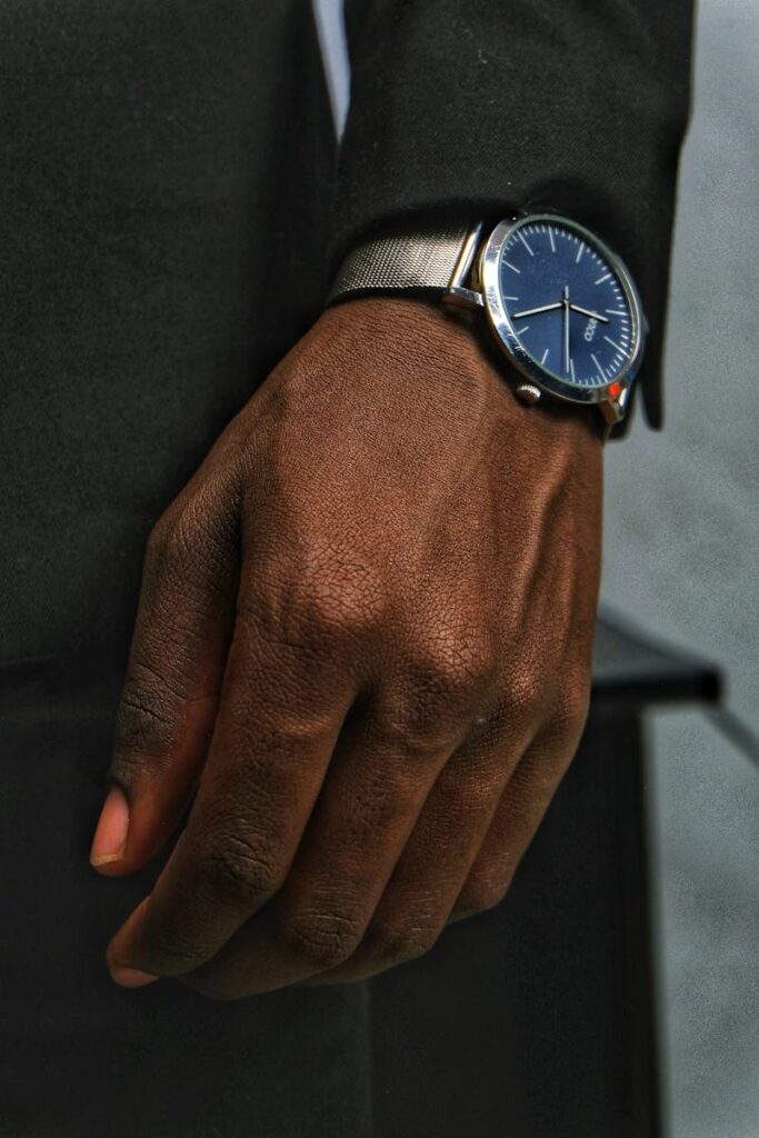 Stylish close-up of a black man's hand wearing an elegant silver wristwatch indoors.