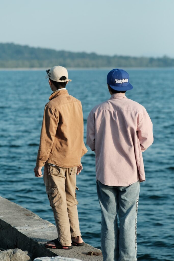 a couple of men standing on top of a pier next to a body of water