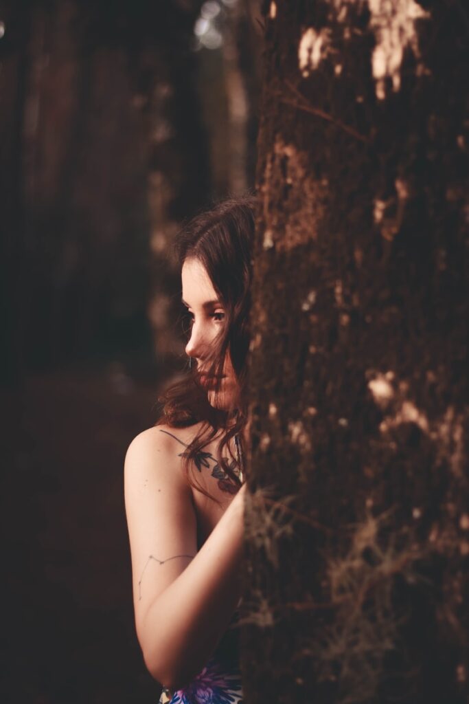 woman in black tank top leaning on tree