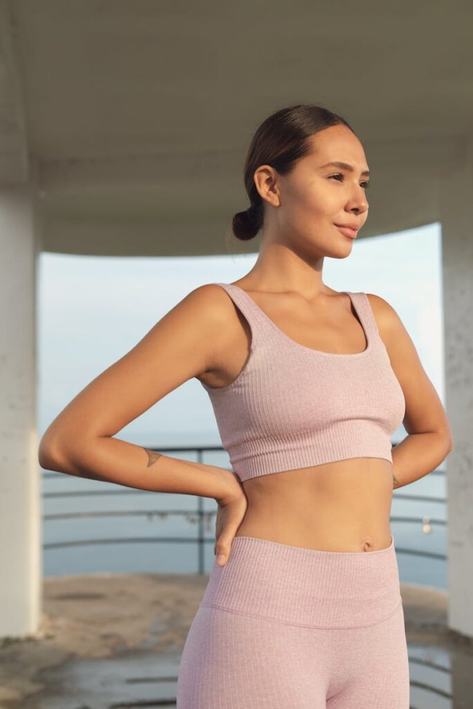 Smiling woman in sports attire enjoying a peaceful outdoor moment during the day.