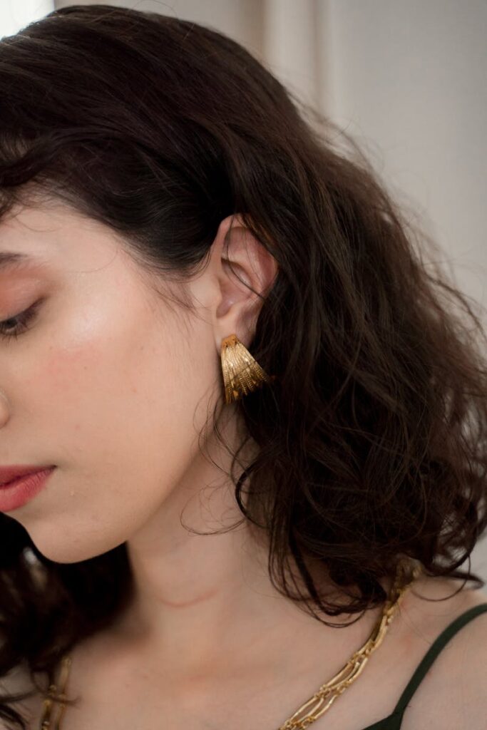 Close-up portrait of a woman wearing a stylish gold earring.