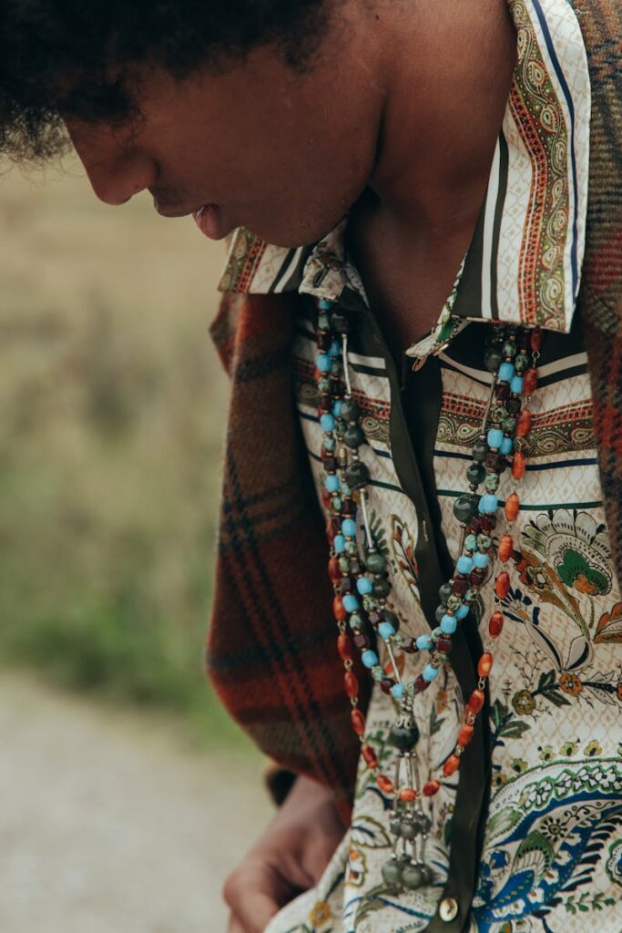 Close-up of a man wearing a tribal-inspired outfit with colorful beaded necklaces outdoors.