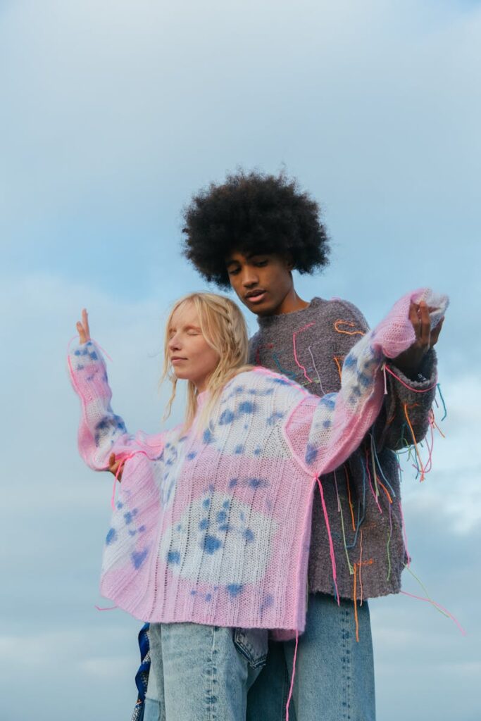 Stylish couple in colorful knit sweaters enjoying a serene outdoor moment.
