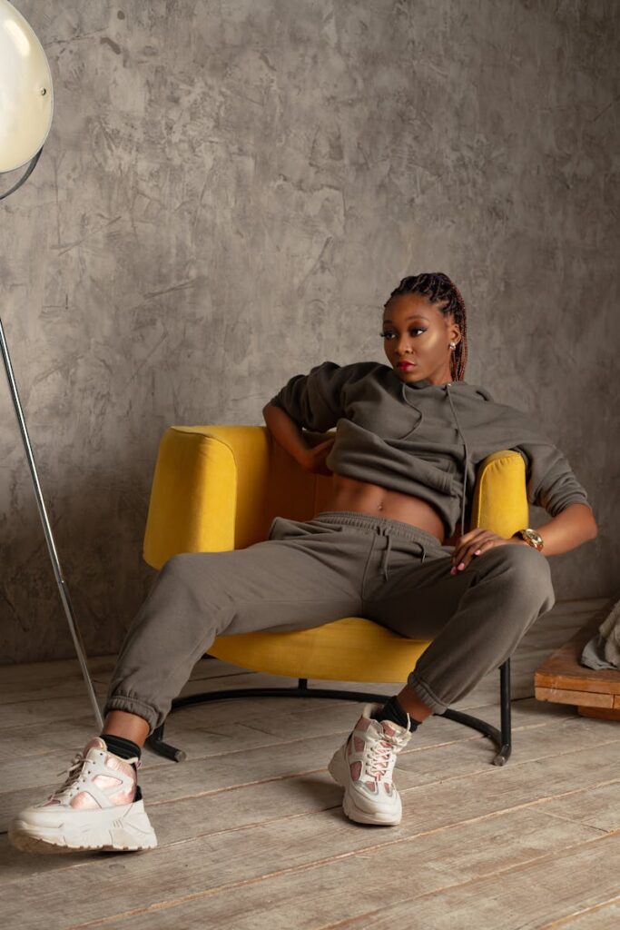 Portrait of a stylish woman lounging in a yellow armchair within a minimalist interior.