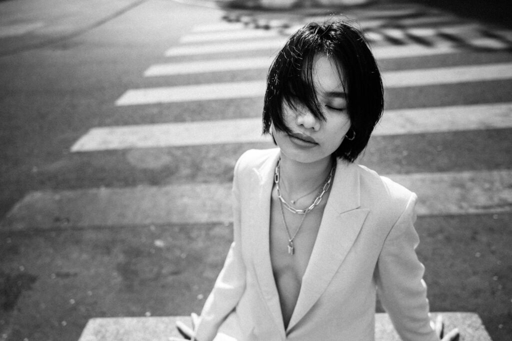 Portrait of a woman in a blazer with eyes closed, sitting at zebra crossing.