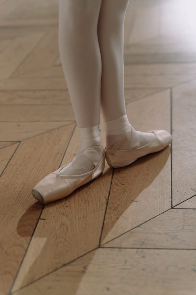 Close-up of ballet shoes on a wooden floor, showcasing grace and poise in a classical dance setting.