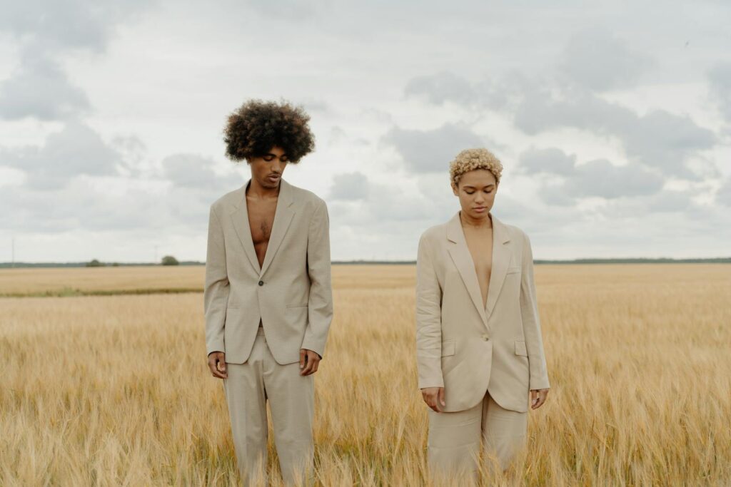 Stylish models in beige suits posing in a serene wheat field.