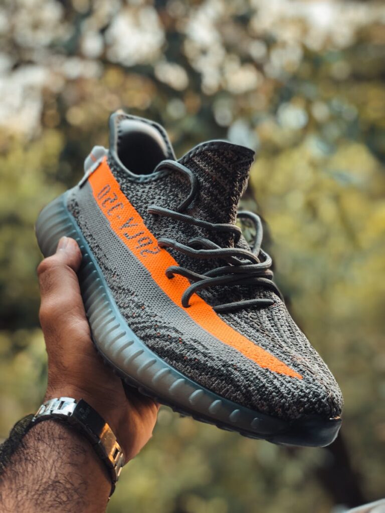 Close-up of a Yeezy sneaker held outdoors with natural background.
