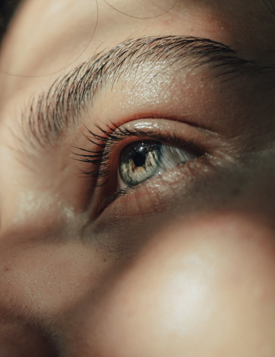 Artistic close-up capture of a blue eye highlighting intricate details and natural sunlight reflections.