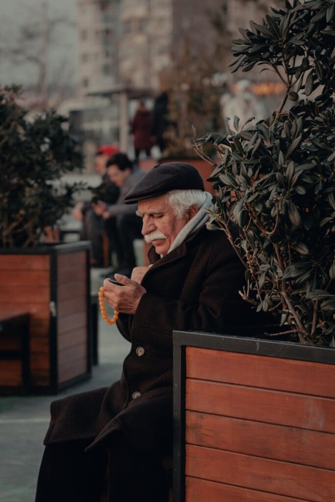 Senior man in winter coat using smartphone while sitting outdoors in Istanbul.