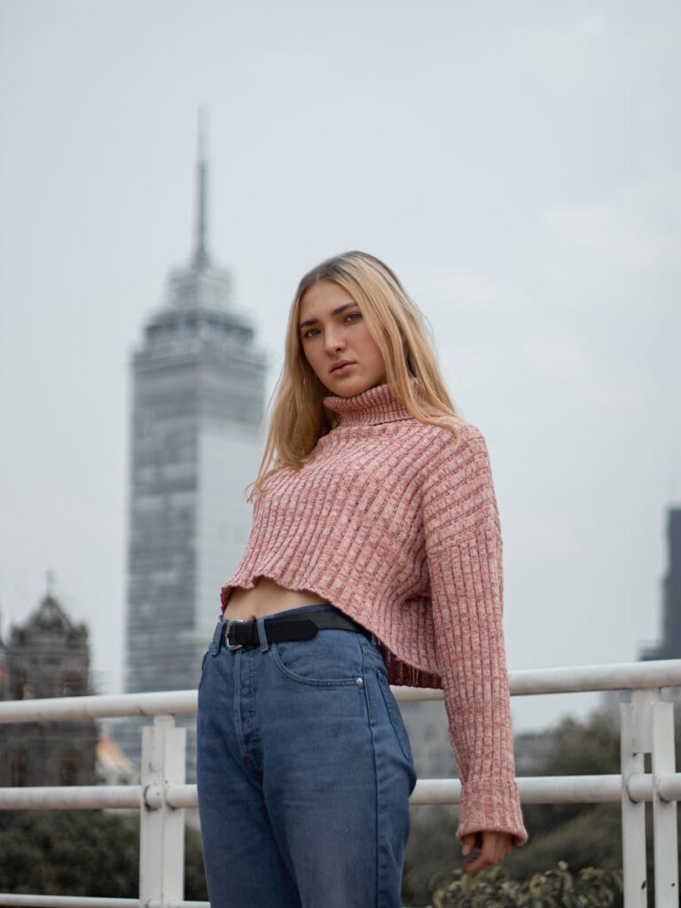 Blonde woman in casual attire posing in front of iconic Mexico City landmark. Urban fashion meets architectural beauty.
