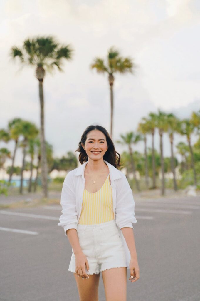 Young woman smiling in a parking lot with palm trees, Tarpon Springs, FL.