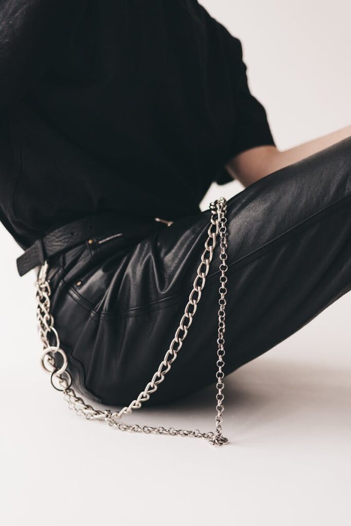 Stylish leather pants highlighted with a metal chain in a studio setting.