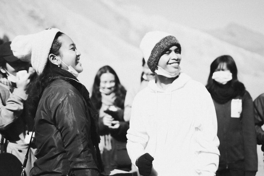 Black and white photo of people wearing face masks and smiling outdoors during pandemic.