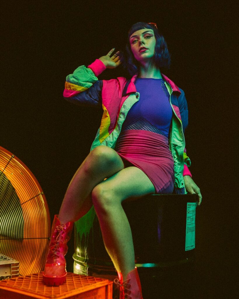 Stylish woman in vibrant outfit with neon lighting, exuding modern fashion vibes.