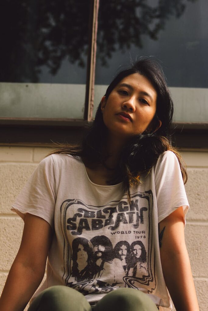 Portrait of a young woman wearing a vintage band T-shirt, captured outdoors on a sunny day.