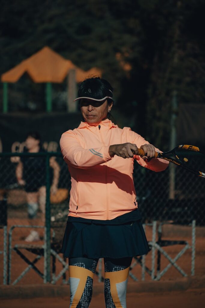 A senior woman in sportswear playing tennis on an outdoor court.