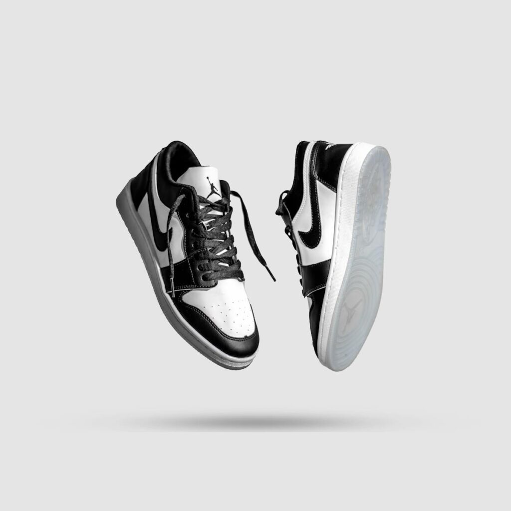 Stylish black and white sneakers floating against a gray background, captured in monochrome style.