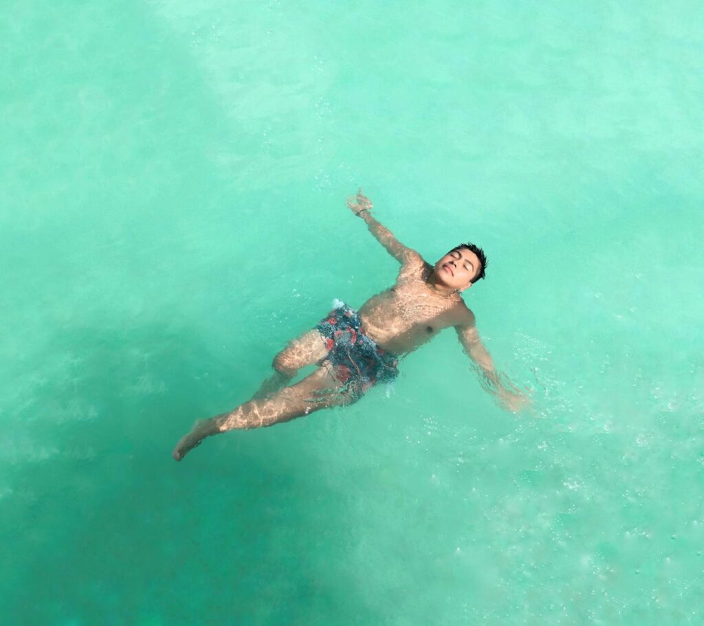 A man floating peacefully in the vibrant turquoise waters of Bacalar, Mexico.