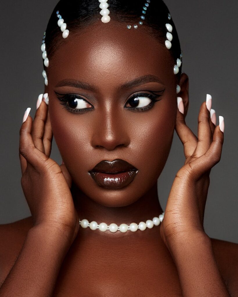 Glamorous studio portrait of a woman adorned with pearl jewelry and bold makeup.