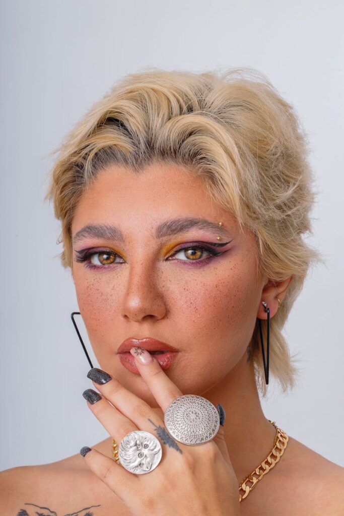 Close-up portrait of a fashionable woman showcasing vibrant makeup and bold jewelry.