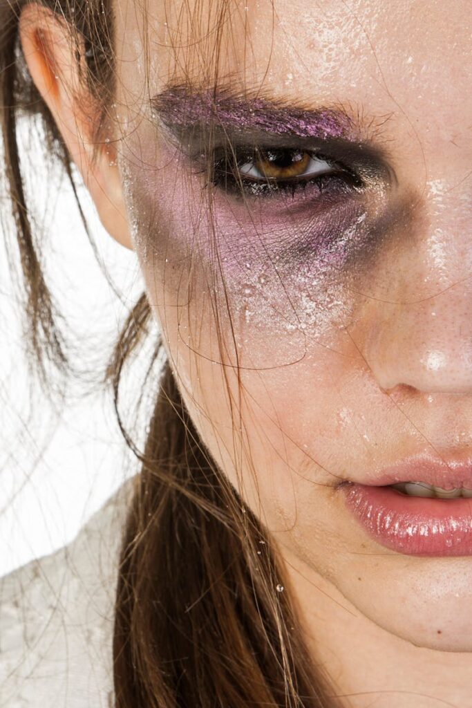 Artistic shot of a woman with smudged makeup conveying emotion and intensity on a white background.