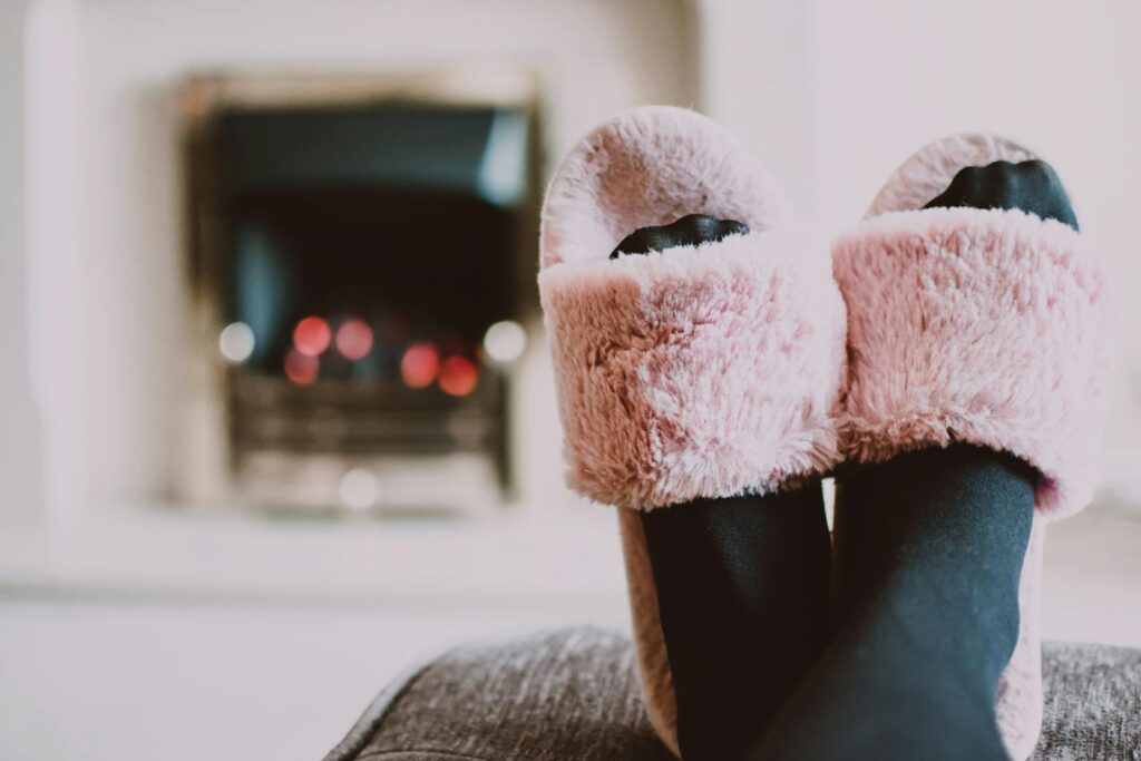 Relaxing by the fireplace with fuzzy slippers and warm socks indoors.
