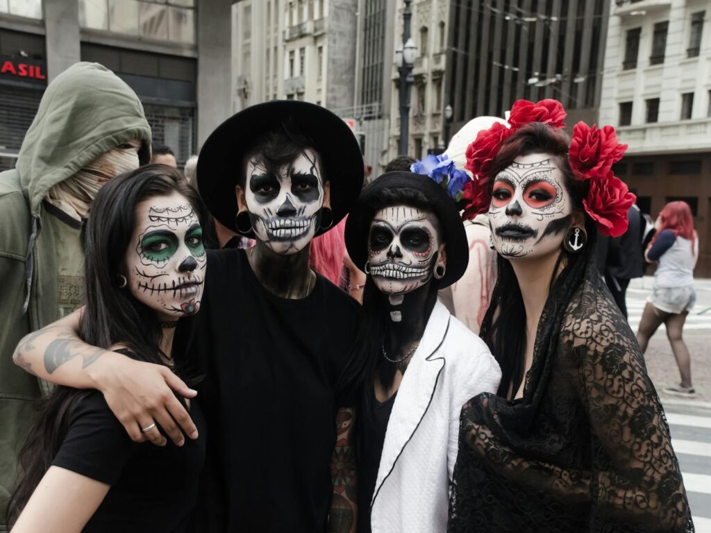 Group of people with creative Day of the Dead face paint celebrating outdoors.