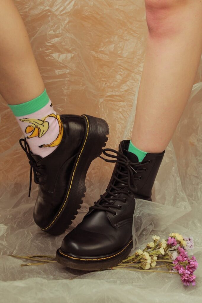 Stylish Doc Martens boots paired with vibrant socks on a plastic background, floral accents.