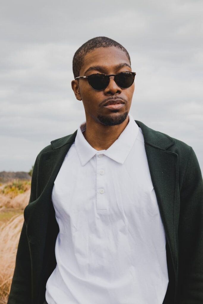 A fashionable man wearing sunglasses enjoying a breezy outdoor day, embodying contemporary style.