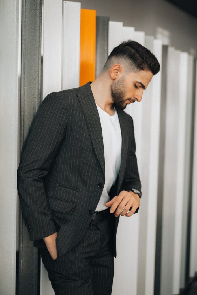 Stylish man in a pinstripe suit looking down indoors. Modern fashion portrait.