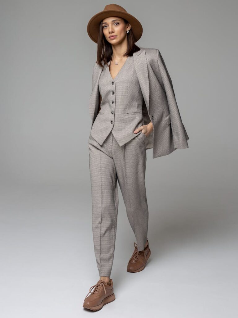 Stylish woman in a tailored gray suit and hat striking a confident pose.
