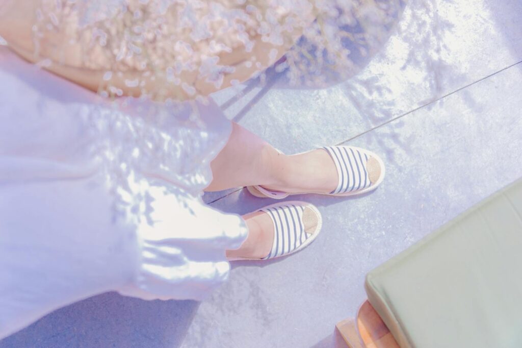 Top view of feet in striped sandals on a sunny day.
