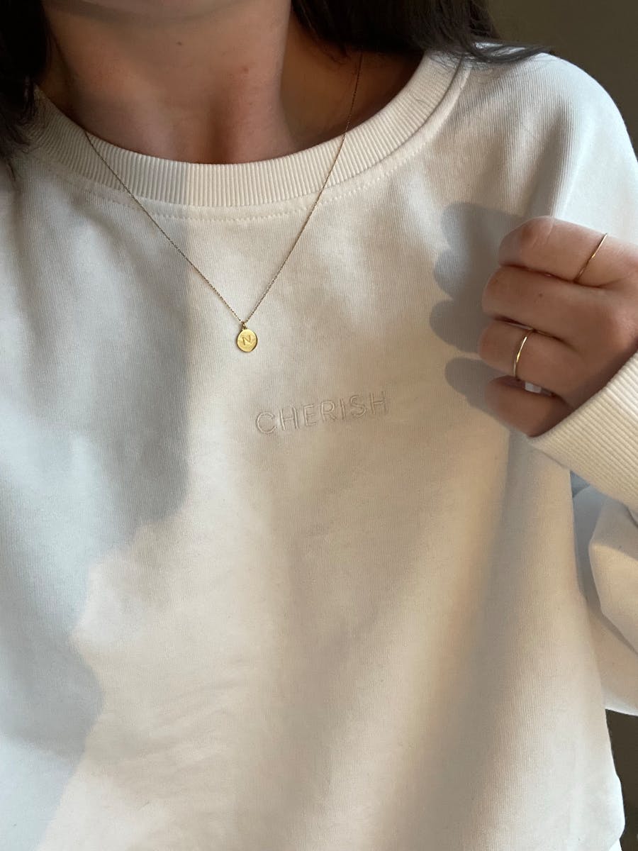 Close-up of a woman wearing a white sweater and gold necklace, showcasing fashion elegance.