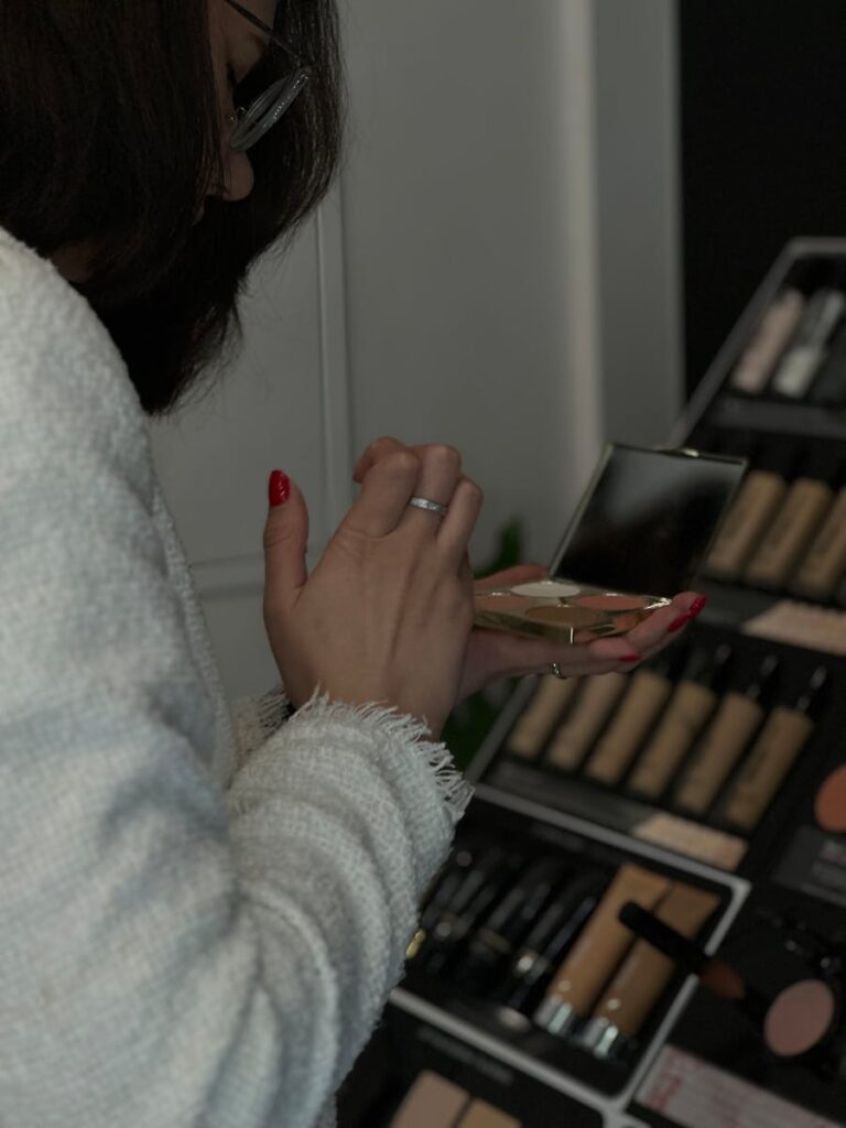 A woman applying makeup using a face palette at a display in Vilnius.