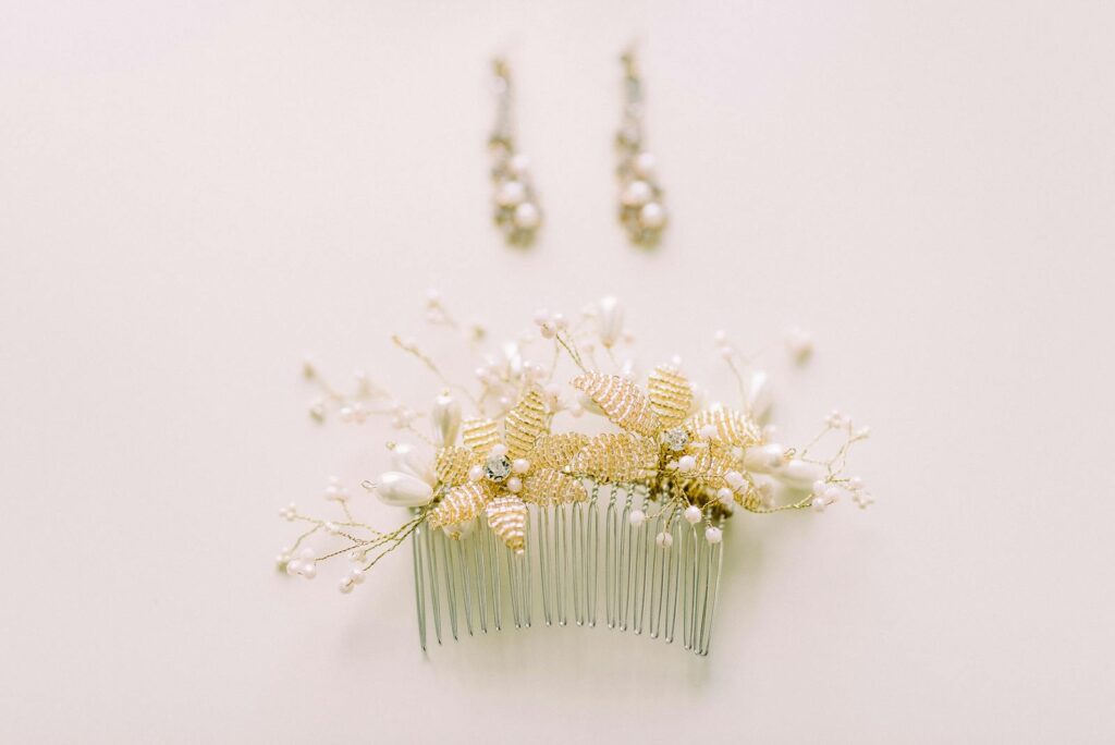 Close-up of an ornate floral hair comb with matching earrings on a soft beige background.
