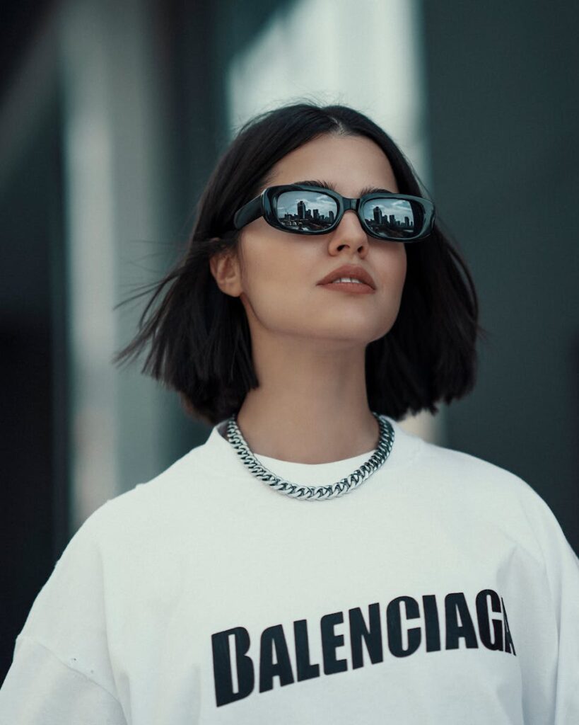 Stylish woman wearing sunglasses and Balenciaga shirt, reflecting Istanbul cityscape.