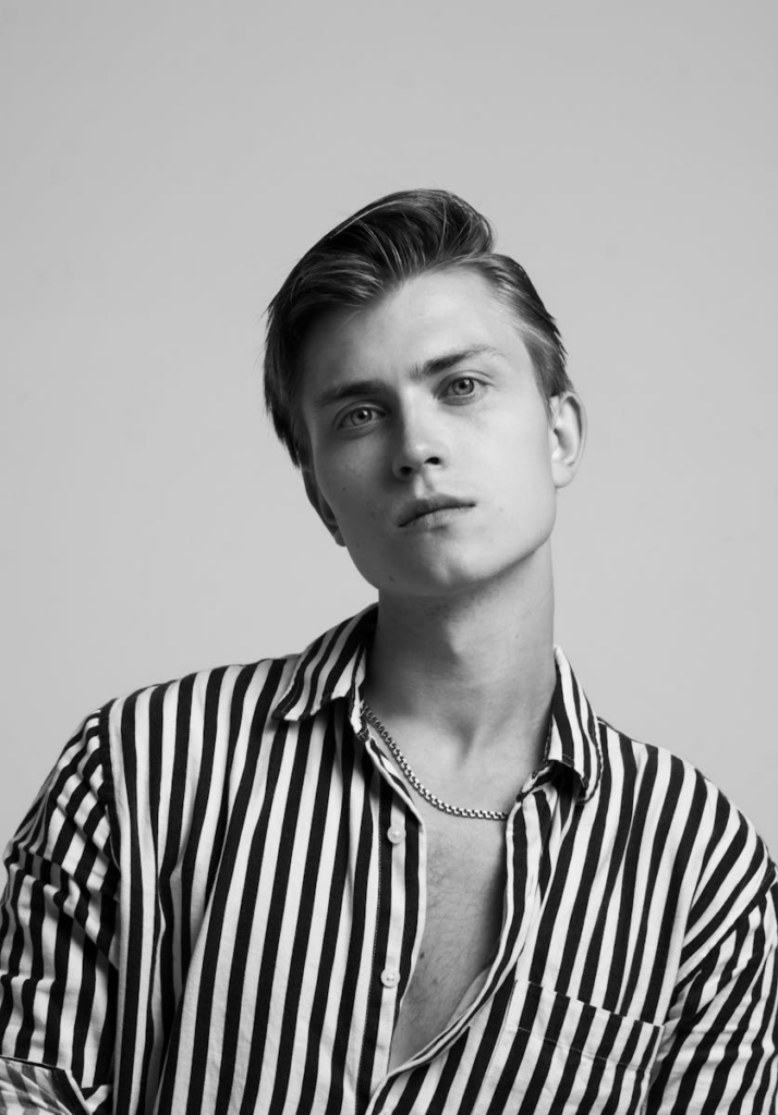 Stylish black and white portrait of a young man posing in a striped shirt.