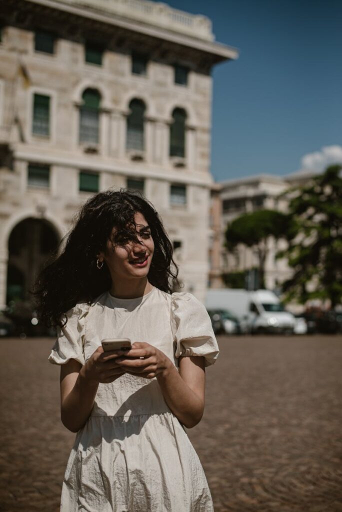 Stylish woman with smartphone enjoying a sunny day in Genoa, Italy.