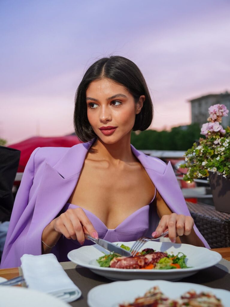 Young woman enjoying an elegant seafood dinner at a beautifully set outdoor restaurant.