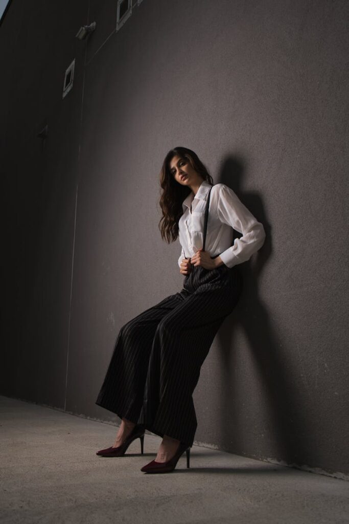 Stylish woman poses against urban wall in chic outfit.