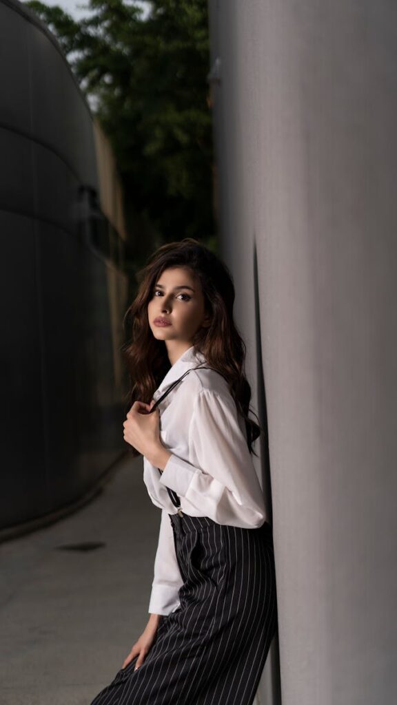 Fashionable woman poses against a modern urban backdrop, showcasing elegance with a blend of contrast and light.